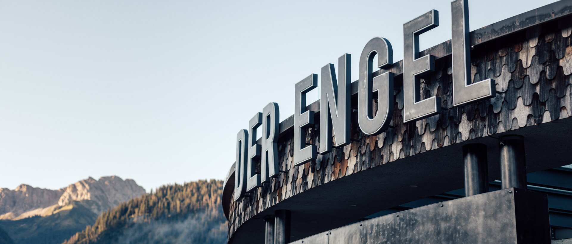 Außenansicht Hotel "Der Engel" mit großem Schriftzug vor Bergkulisse