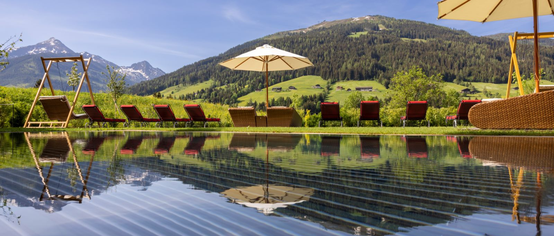 Pool mit Liegen und Sonnenschirm vor Berglandschaft