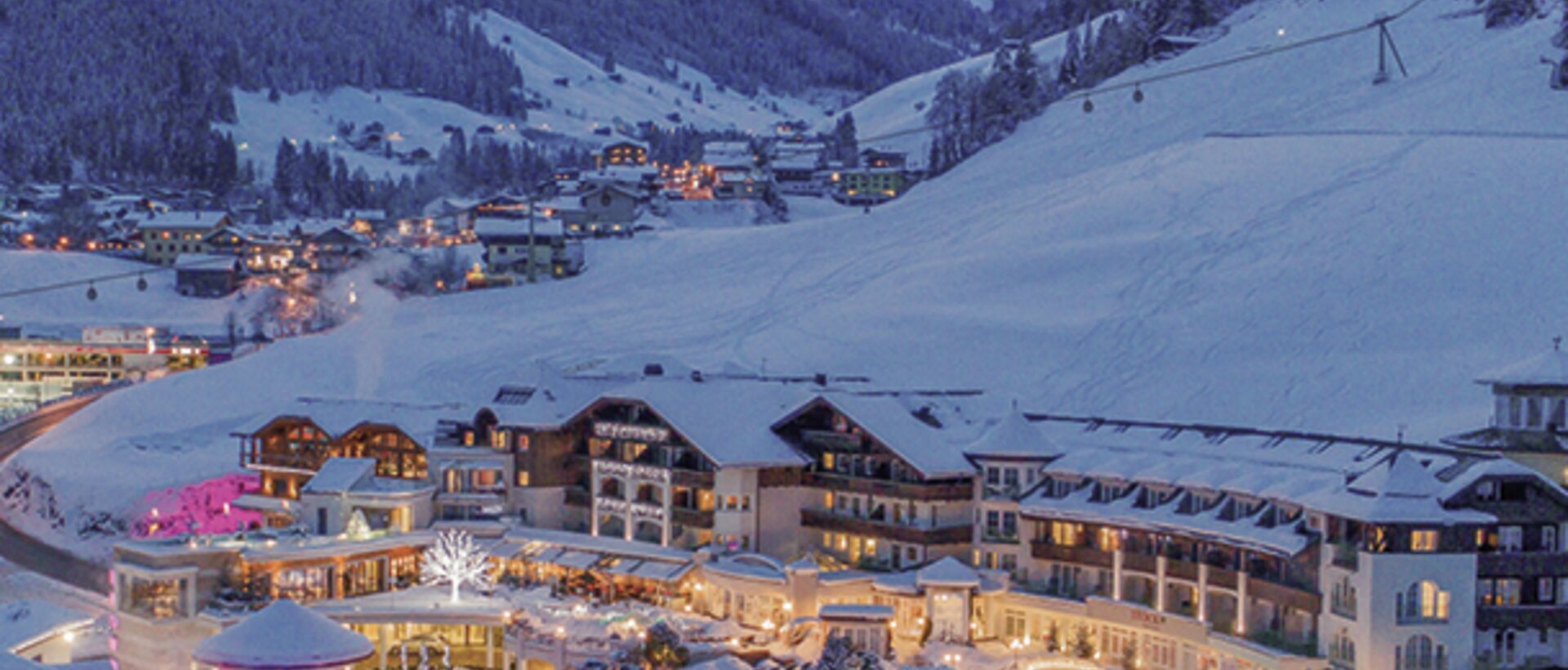 Hotelanlage im Winterort mit schneebedeckten Bergen im Hintergrund