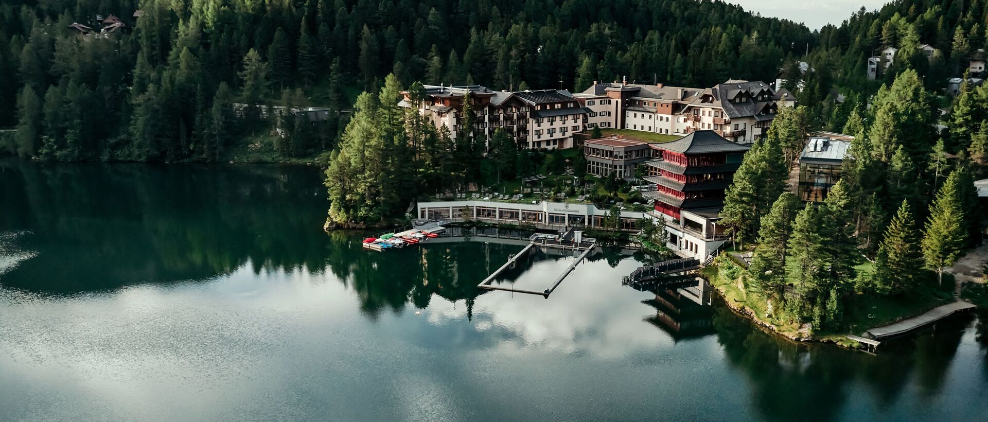 Hotelanlage am See, umgeben von Wald und Bergen