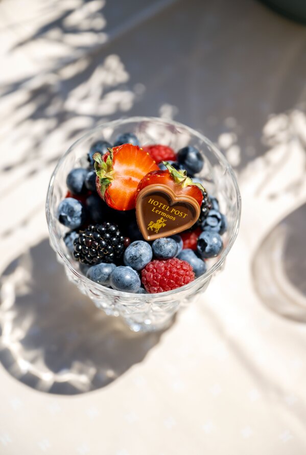 Glas mit frischen Beeren und Schokoladenherz.