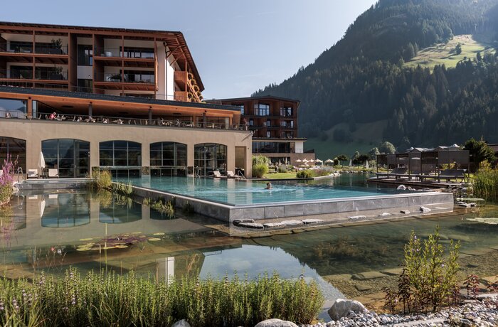 Modernes Wellnesshotel mit großzügigem Naturpool und traumhaftem Bergpanorama – Ruhe und Erholung inmitten der Alpen.