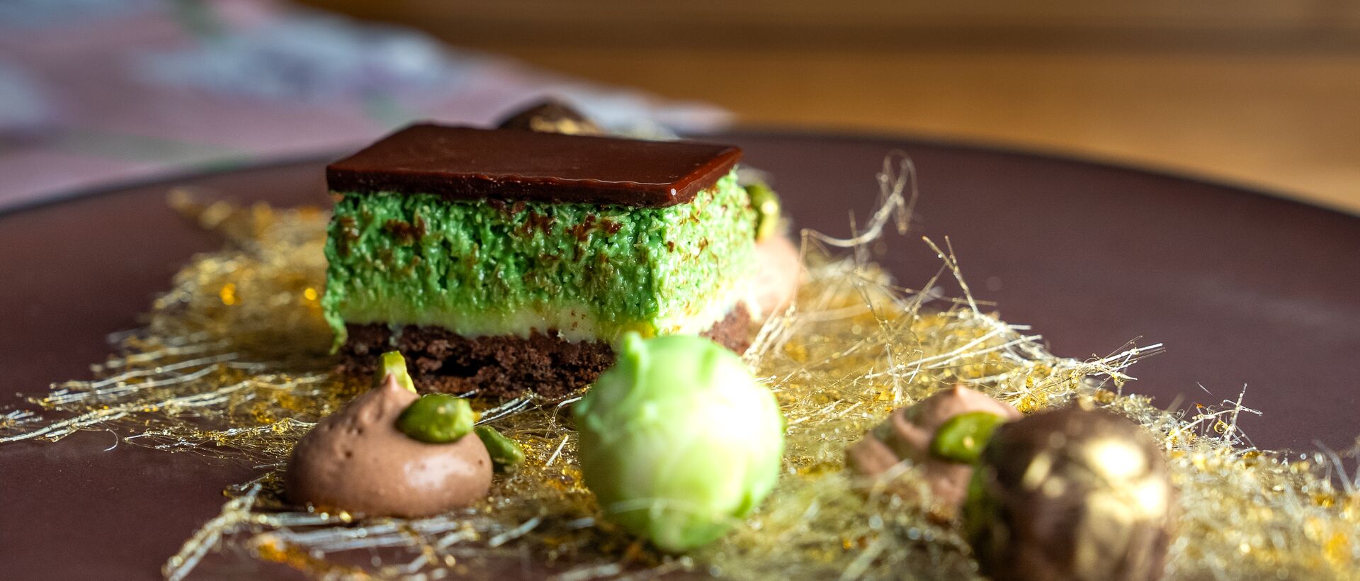 Kreativ angerichtetes Schokoladendessert auf dunklem Teller mit feinen Dekorationen und Pralinen