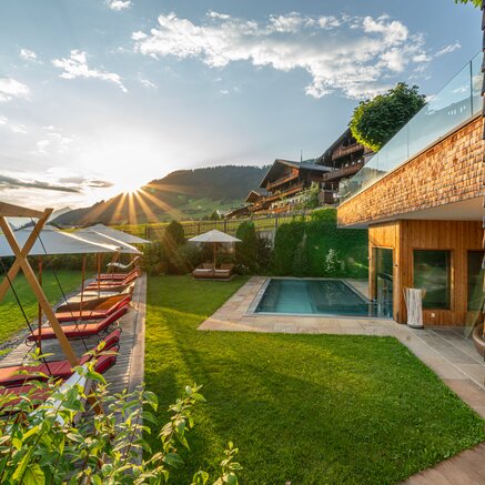 Outdoor area with pool, sun loungers and mountain view at sunset