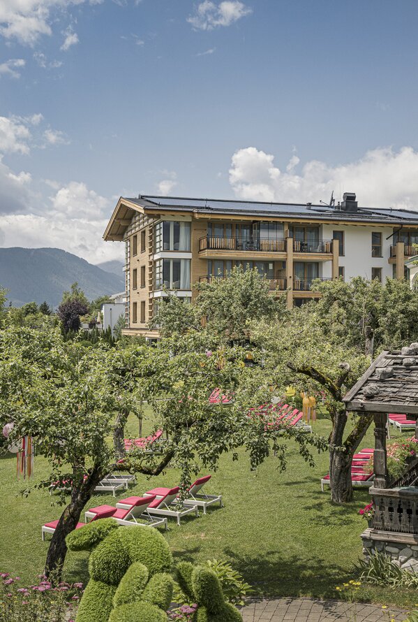 Hotelgarten mit Liegewiesen, alten Bäumen und entspannter Atmosphäre in alpiner Umgebung.