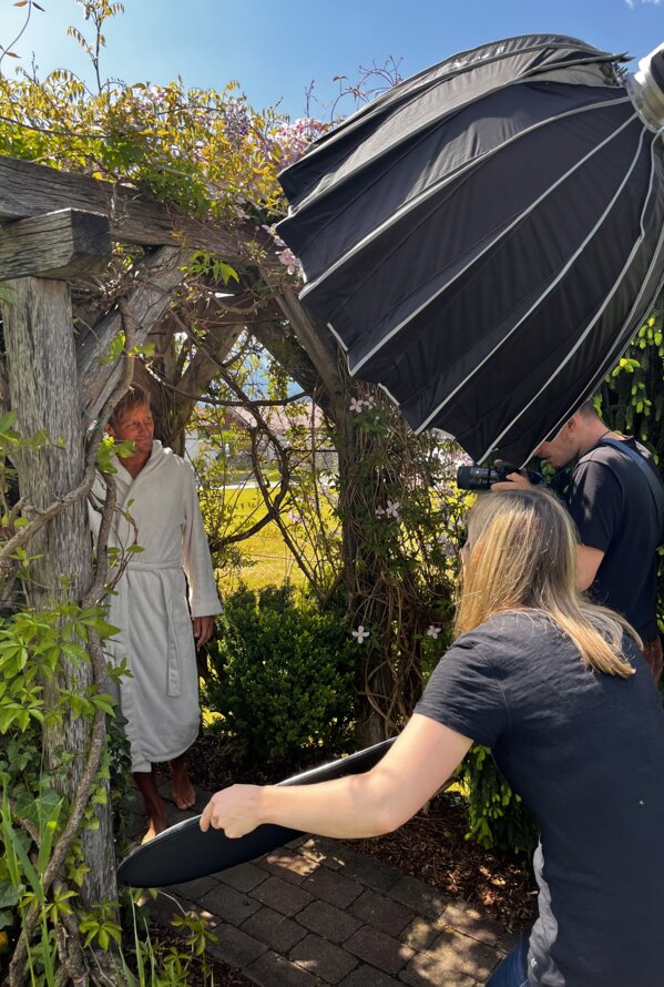 Mann im Bademantel posiert für Fotoshooting im Garten