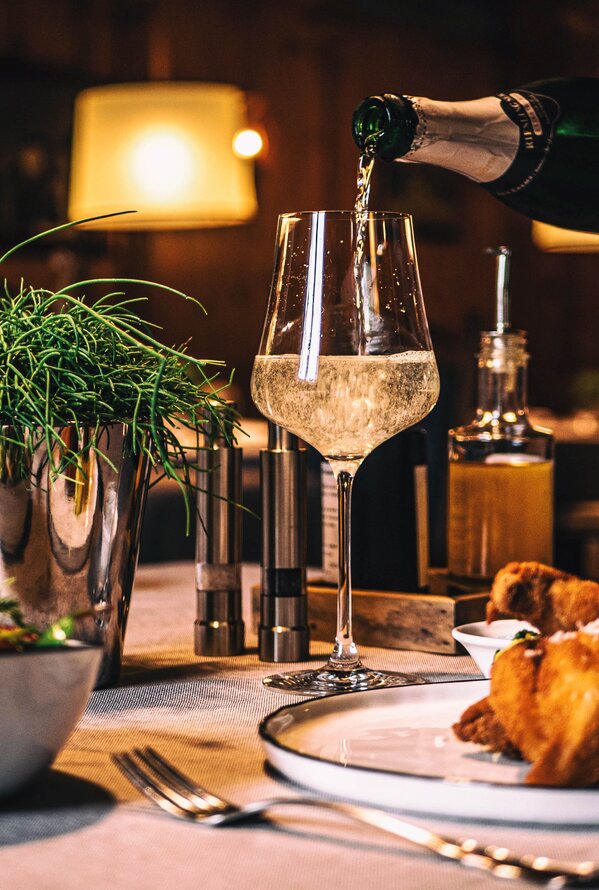 Table set with salad, schnitzel and sparkling wine being poured into a glass