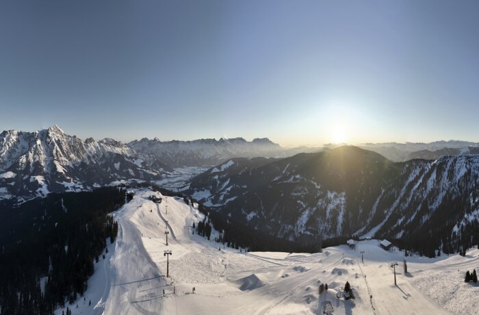 Winterliche Berglandschaft mit Skipiste und strahlender Sonne
