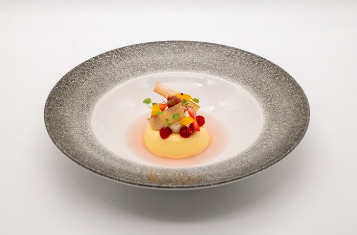 Dessert with yellow pudding, fruits and decoration on a plate