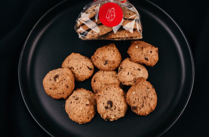 Gingerbread on a black plate, some loose, others wrapped in foil with a red ribbon