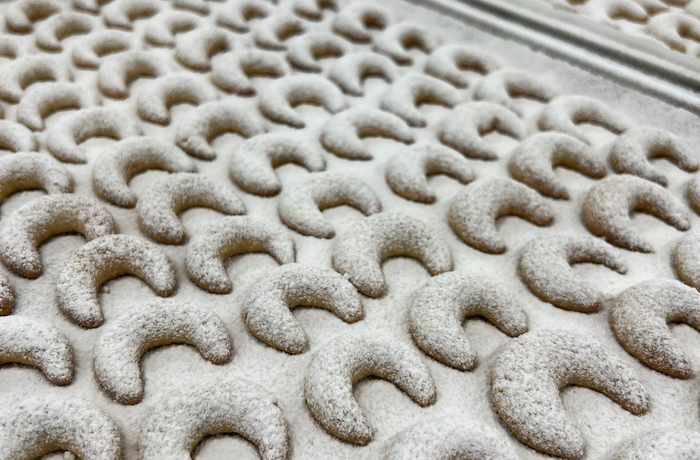 Trays with lots of vanilla crescents, dusted with powdered sugar