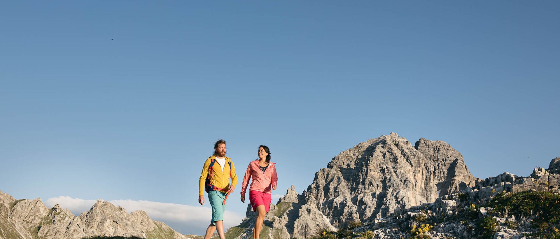 Wanderndes Paar in Berglandschaft vor blauem Himmel