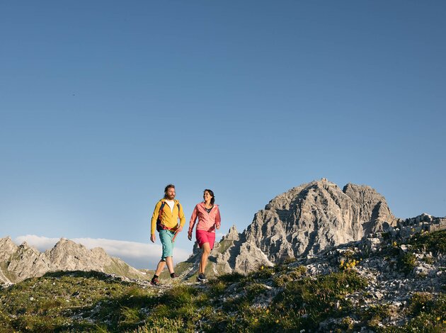 Wanderndes Paar in Berglandschaft vor blauem Himmel