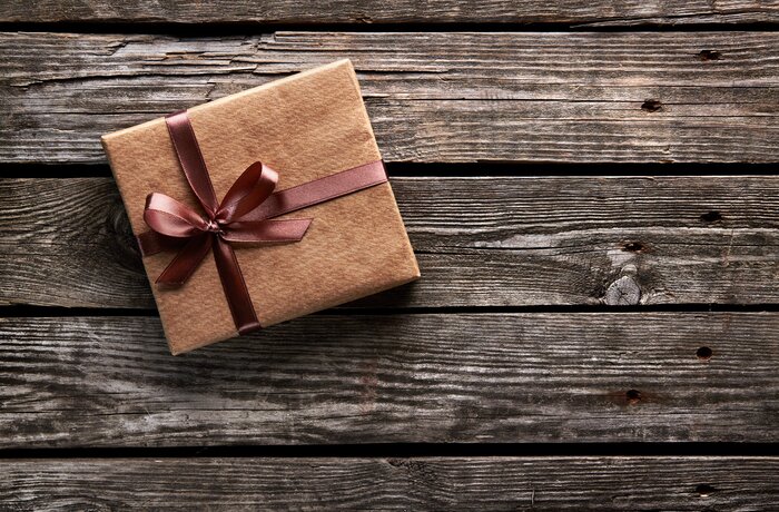 Gift in brown paper with bow on dark wood