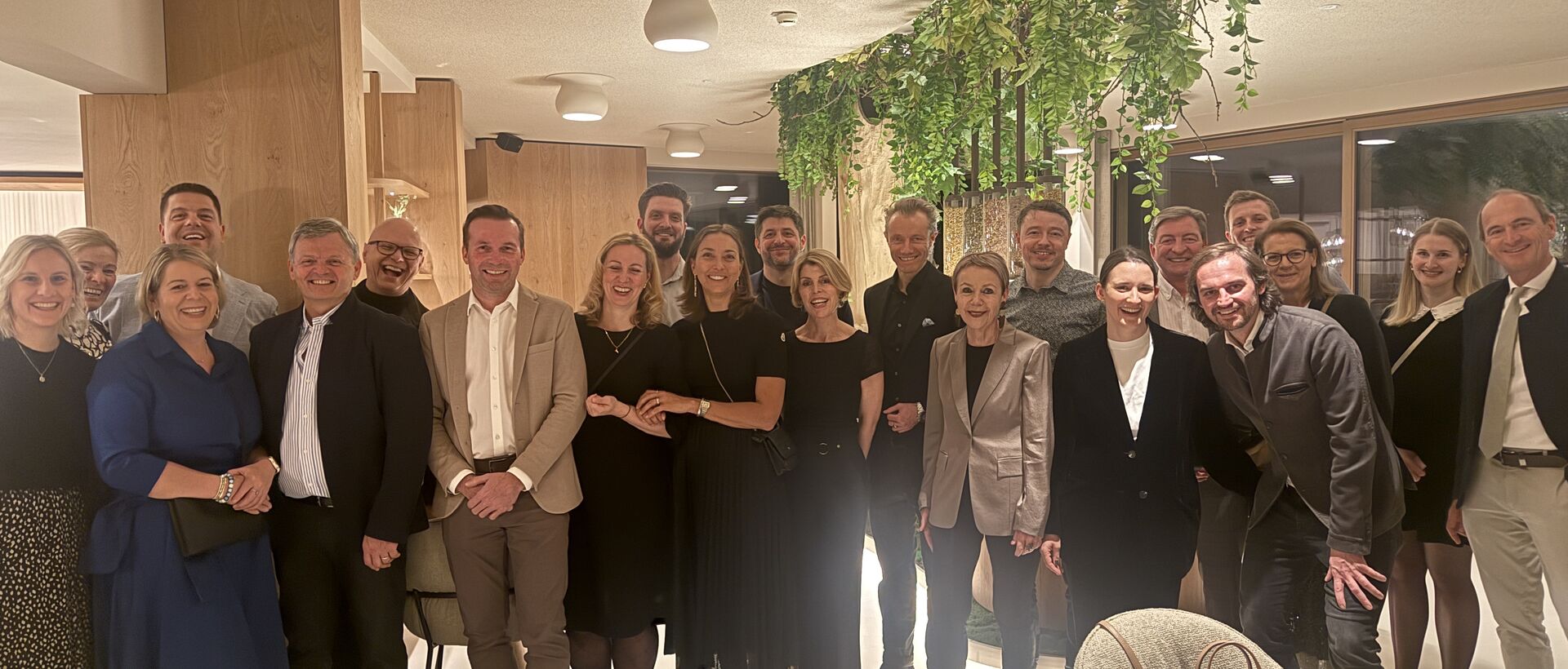 Gruppenfoto von Gästen und Gastgebern in stilvollem Restaurantambiente.