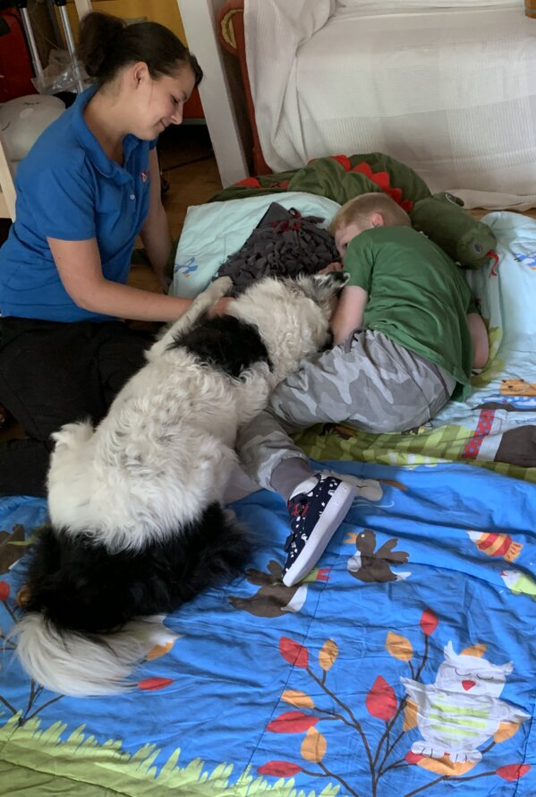 Kind mit Hund und Betreuungsperson auf einer Spielmatte