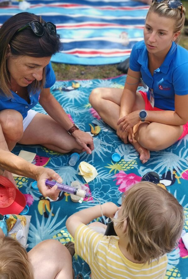 Zwei Frauen betreuen Kinder bei einem Picknick im Freien.