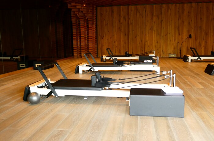 Reformer-Pilates-Geräte im stilvollen Trainingsraum des Reformer Retreats mit hellem Holzboden und warmem Holzambiente.