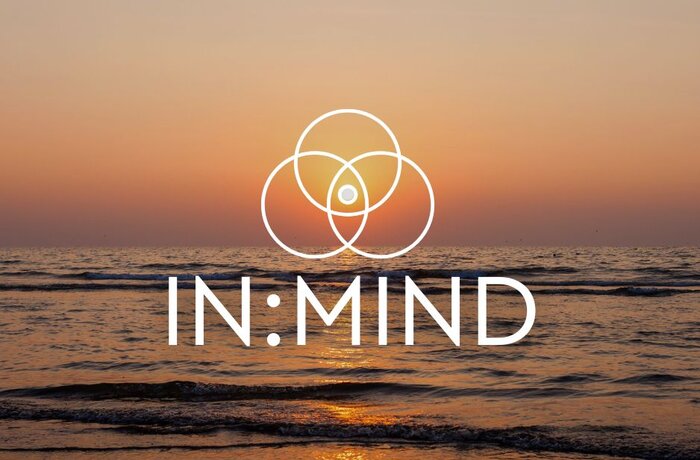 Ruhiger Sonnenuntergang am Meer mit dem IN:MIND-Logo als Symbol für Achtsamkeit, Balance und Entspannung.