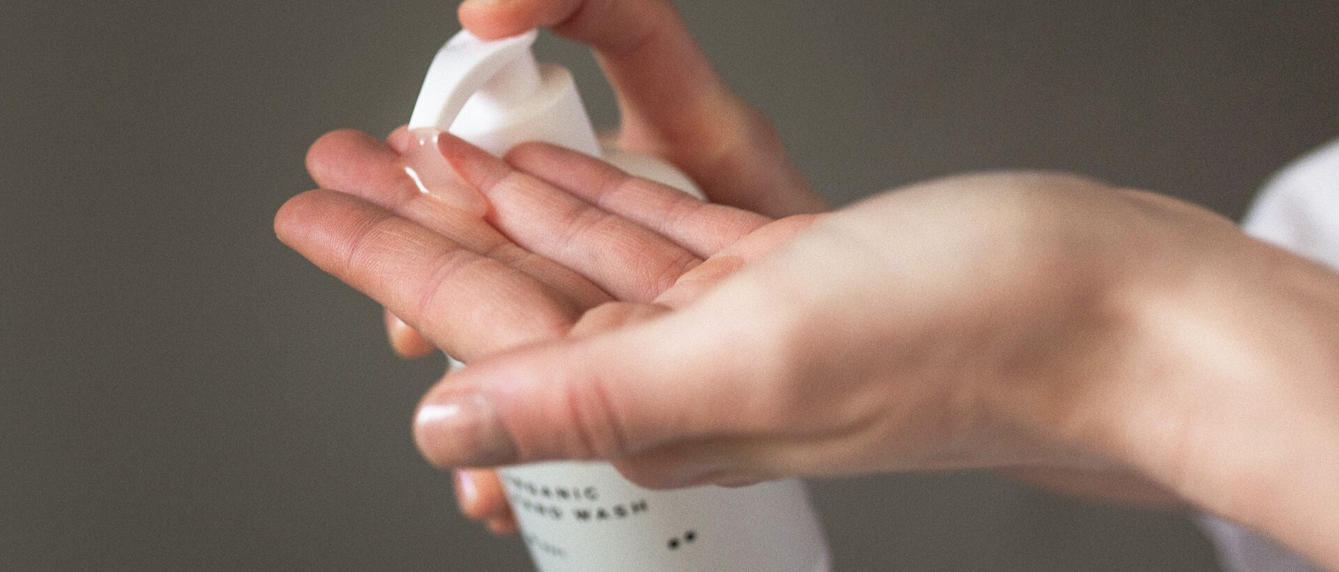 Hand pumpt Flüssigkeit aus weißer Flasche in Handfläche