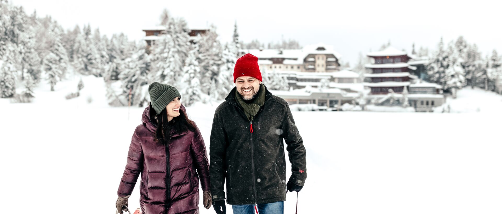 Smiling couple with sledge in winter landscape