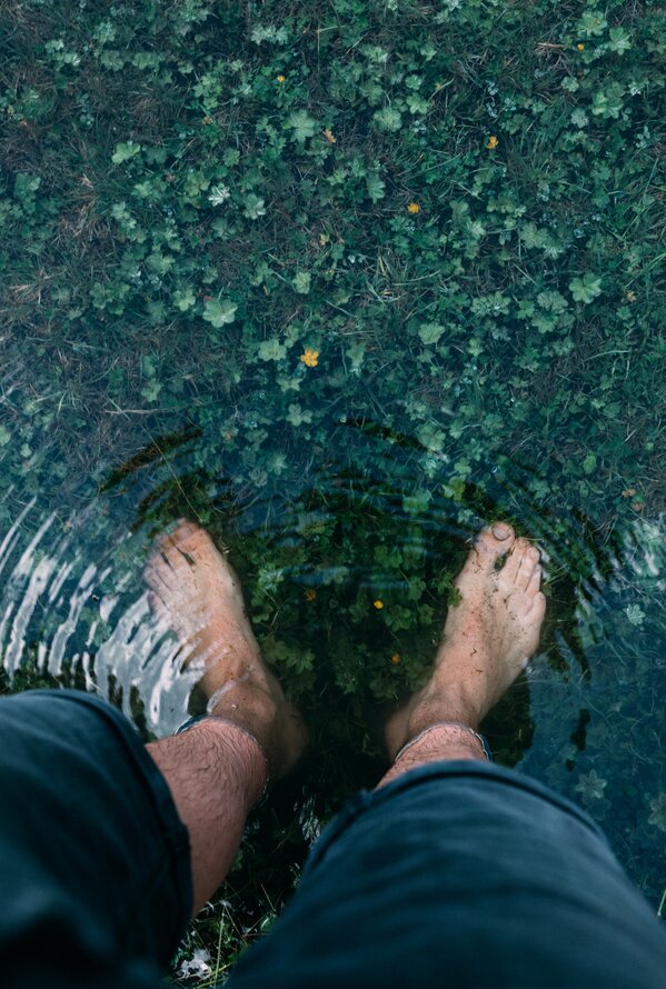 Füße im Wasser, Spiegelung von Gras und Blättern