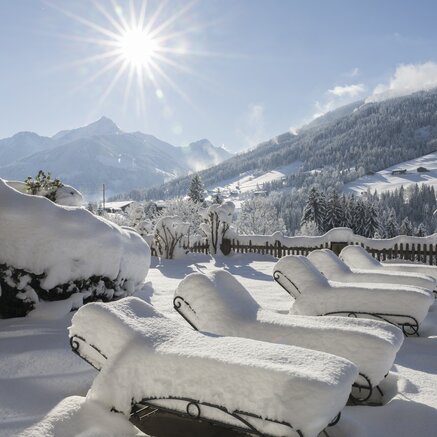 Verschneite Liegen am Pool, Winterlandschaft mit Bergen im Hintergrund