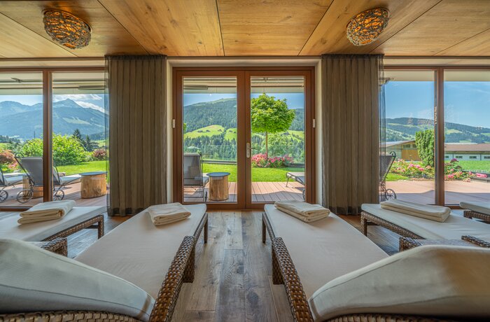 Panoramaruheraum mit Liegen und Ausblick auf grüne Hügellandschaft durch große Fenster