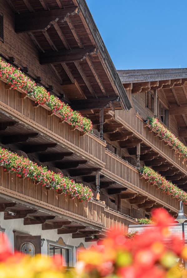 Holzfassade mit blumengeschmückten Balkonen unter blauem Himmel