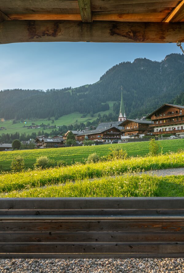 Schaukel vor Bergdorf mit Kirche im Abendlicht