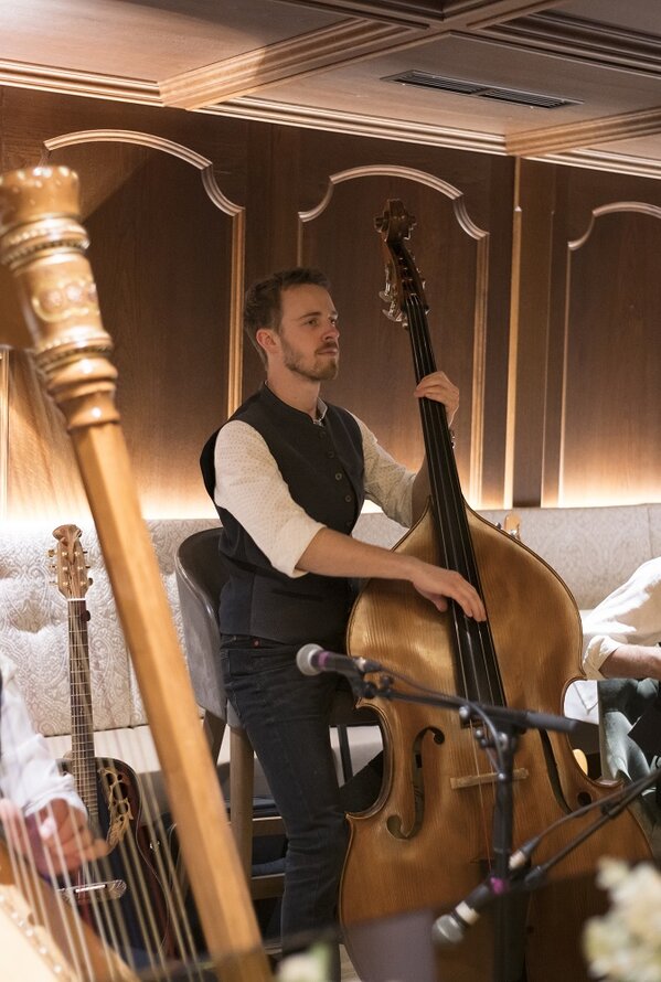 Musiker mit Harfe, Kontrabass und Akkordeon spielen in einem Raum
