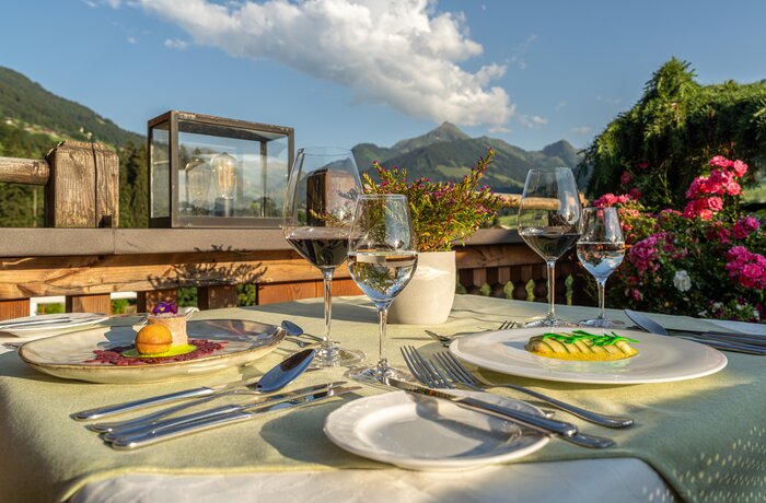 Gedeckter Tisch mit Speisen und Getränken vor Bergpanorama im Alpbacherhof