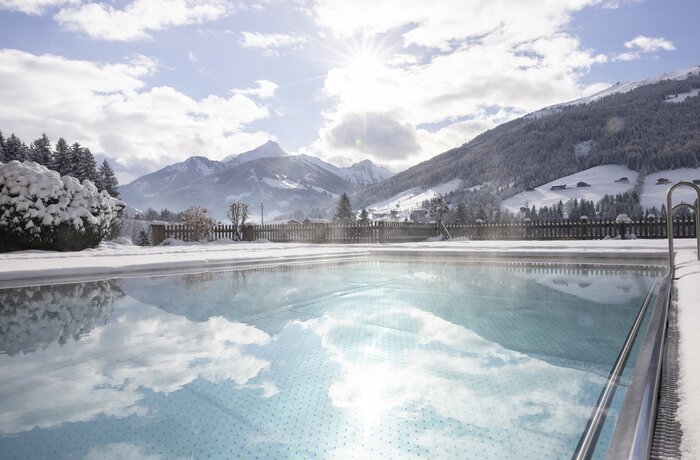 Winterlicher Außenpool mit Bergpanorama und Schnee im Alpbacherhof