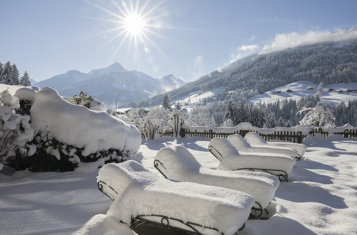 Verschneite Liegen am Pool, Winterlandschaft mit Bergen im Hintergrund