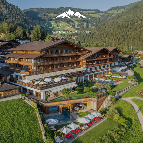 Luftaufnahme eines Resorts mit Poolbereich, Sonnenterrassen und Berglandschaft