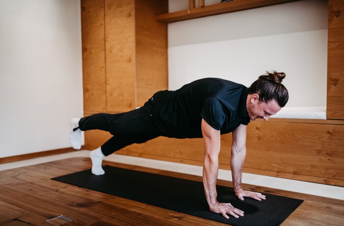 Mann macht Plank mit angehobenem Bein auf Yogamatte