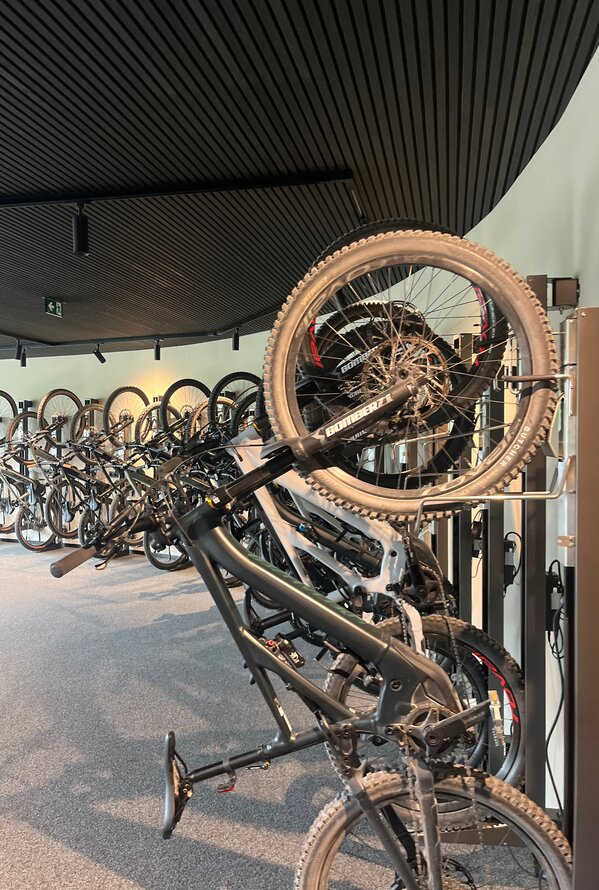 Bicycles in a bicycle room, some hanging on the wall