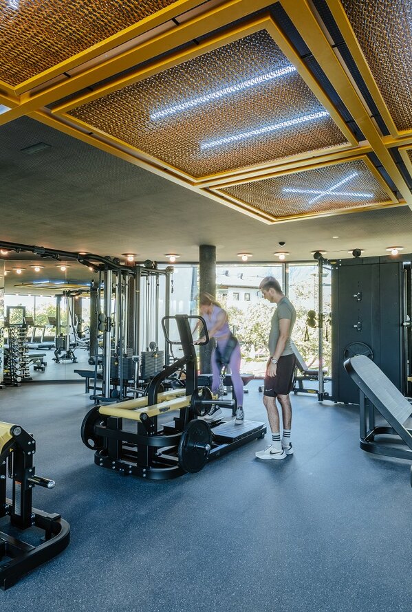 Bright gym with equipment, people and striking ceiling construction