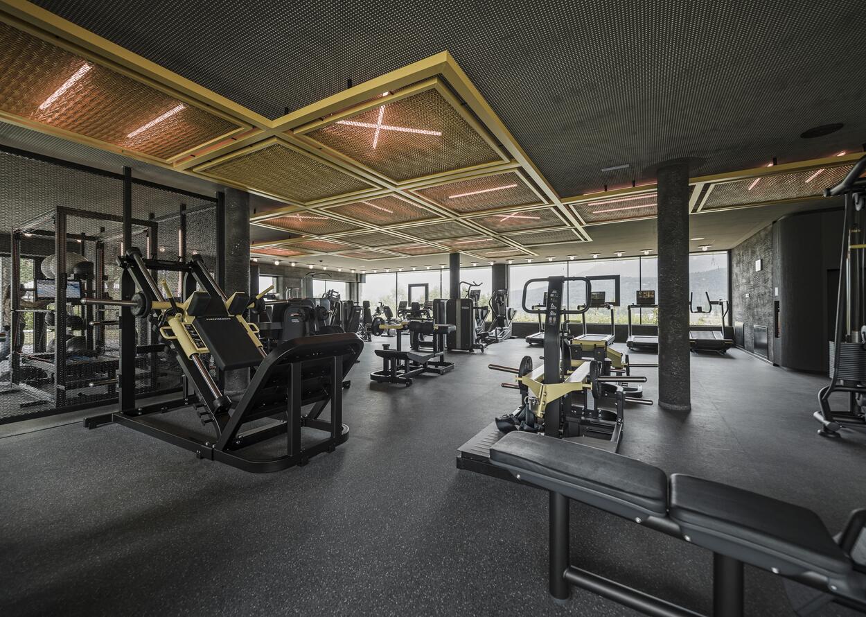 Fitnessstudio mit schwarzen Geräten und Deckenkonstruktion mit gelben Akzenten