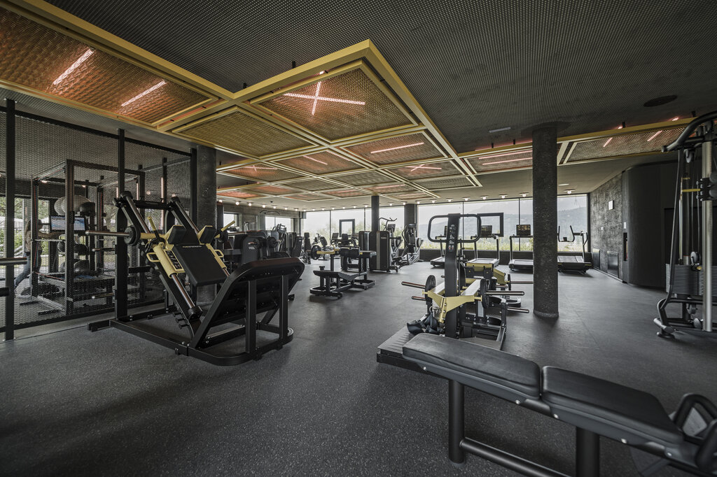 Fitnessstudio mit schwarzen Geräten und Deckenkonstruktion mit gelben Akzenten