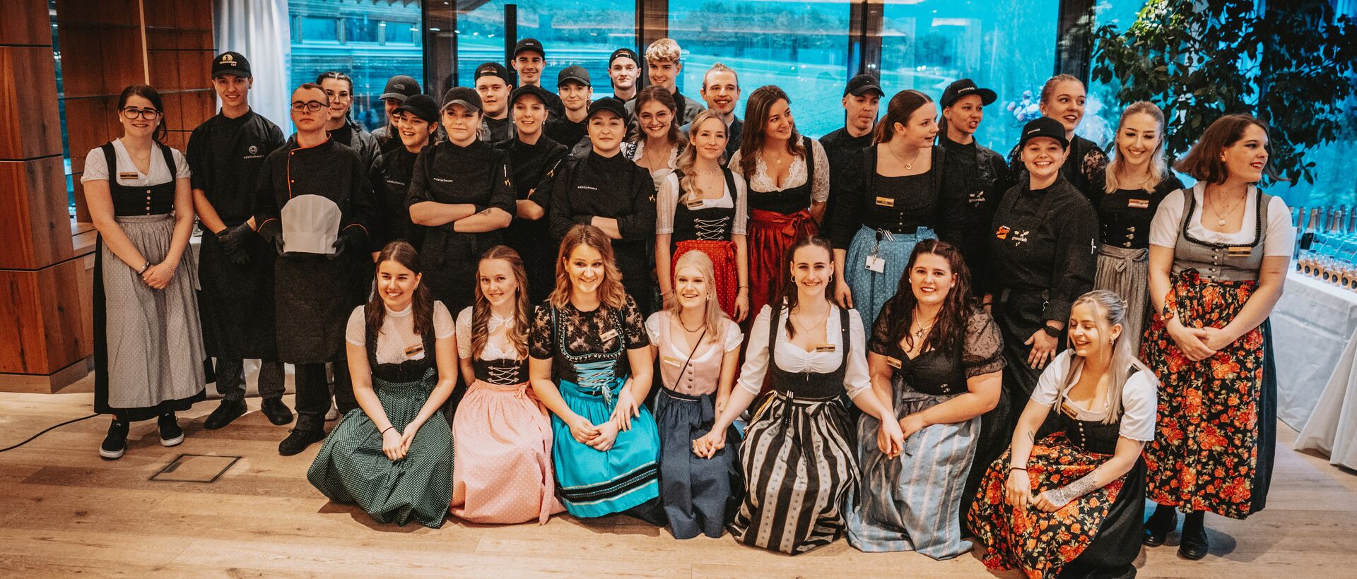 Gruppe junger Menschen in Kochkleidung und Dirndl posiert für ein Foto