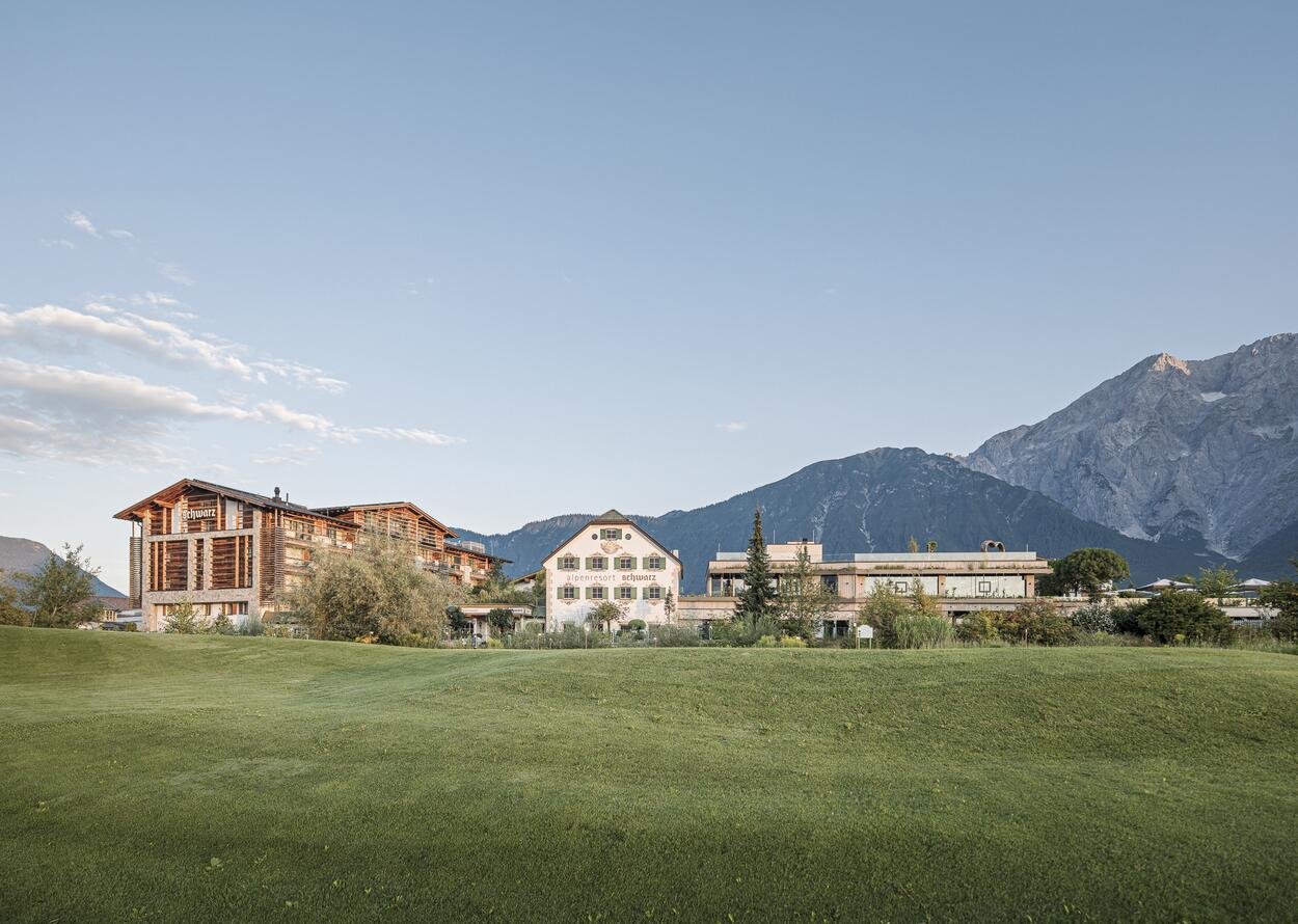 Alpenresort Schwarz mit Bergen im Hintergrund unter blauem Himmel