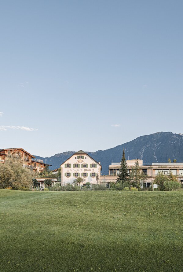 Alpenresort Schwarz mit Bergen im Hintergrund unter blauem Himmel
