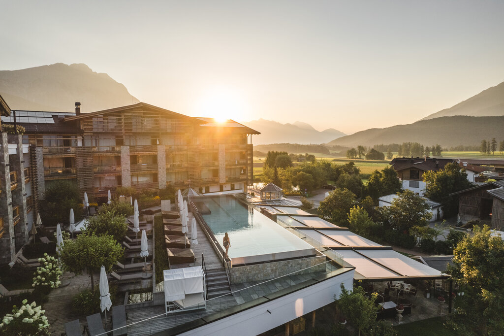 Aerial view of a hotel with infinity pool and mountain panorama at sunset