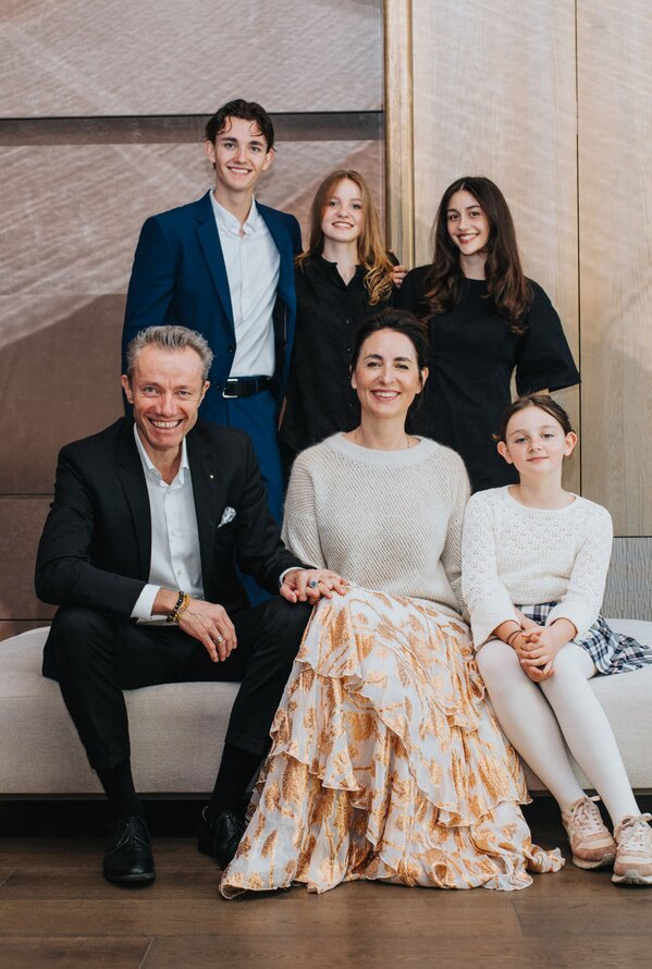 Familie sitzt und steht gemeinsam lächelnd in einer modernen Hotellobby
