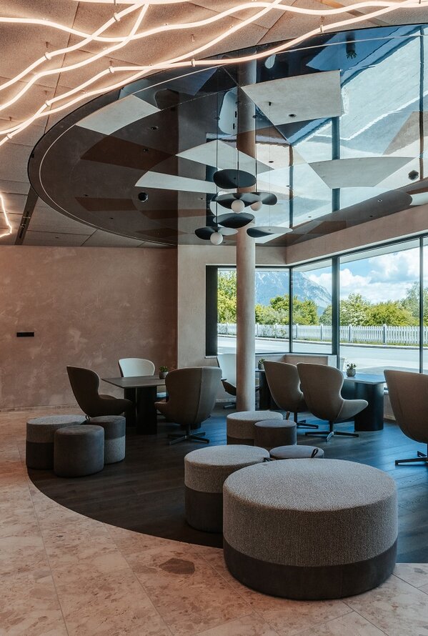 Modern reception area with seating, large windows and striking ceiling lighting