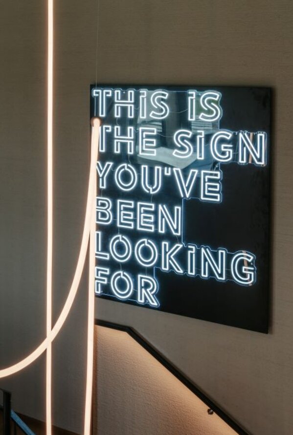 Neon artwork with lettering above stairs