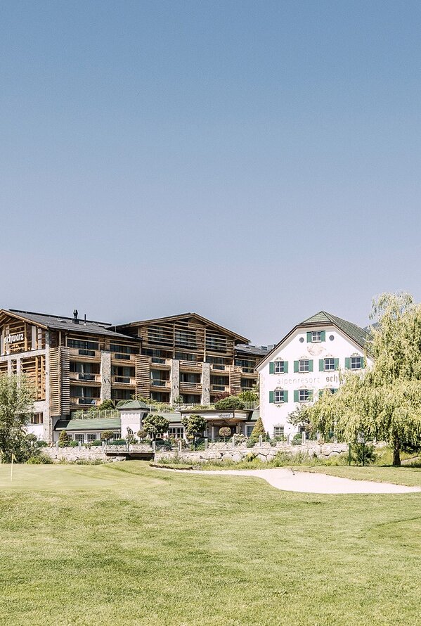 Hotelanlage mit Golfplatz im Sommer vor Bergkulisse