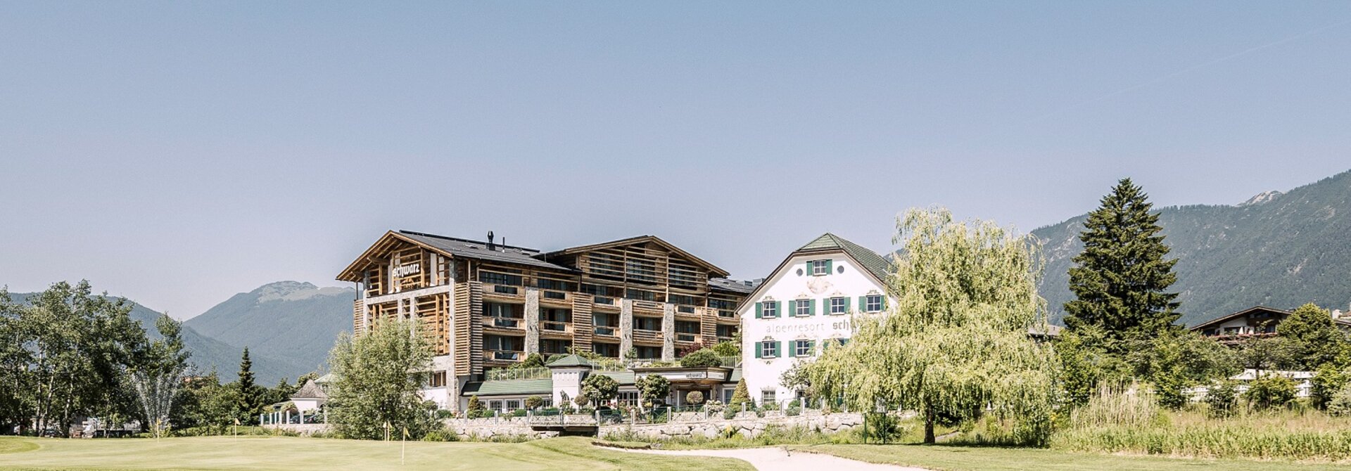 Hotelanlage mit Golfplatz im Sommer vor Bergkulisse