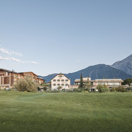 Alpenresort Schwarz in front of green meadow and mountain backdrop under blue sky